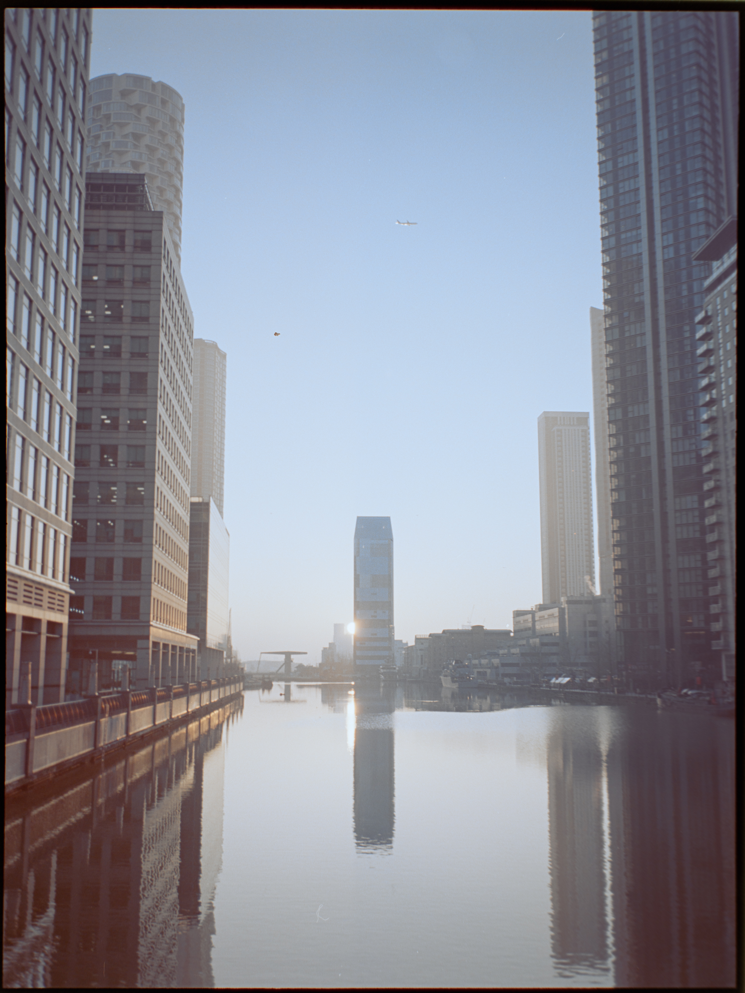 Person walking through Canary Wharf with modern glass buildings — street photography on Kodak Portra 160 by David McConaghy