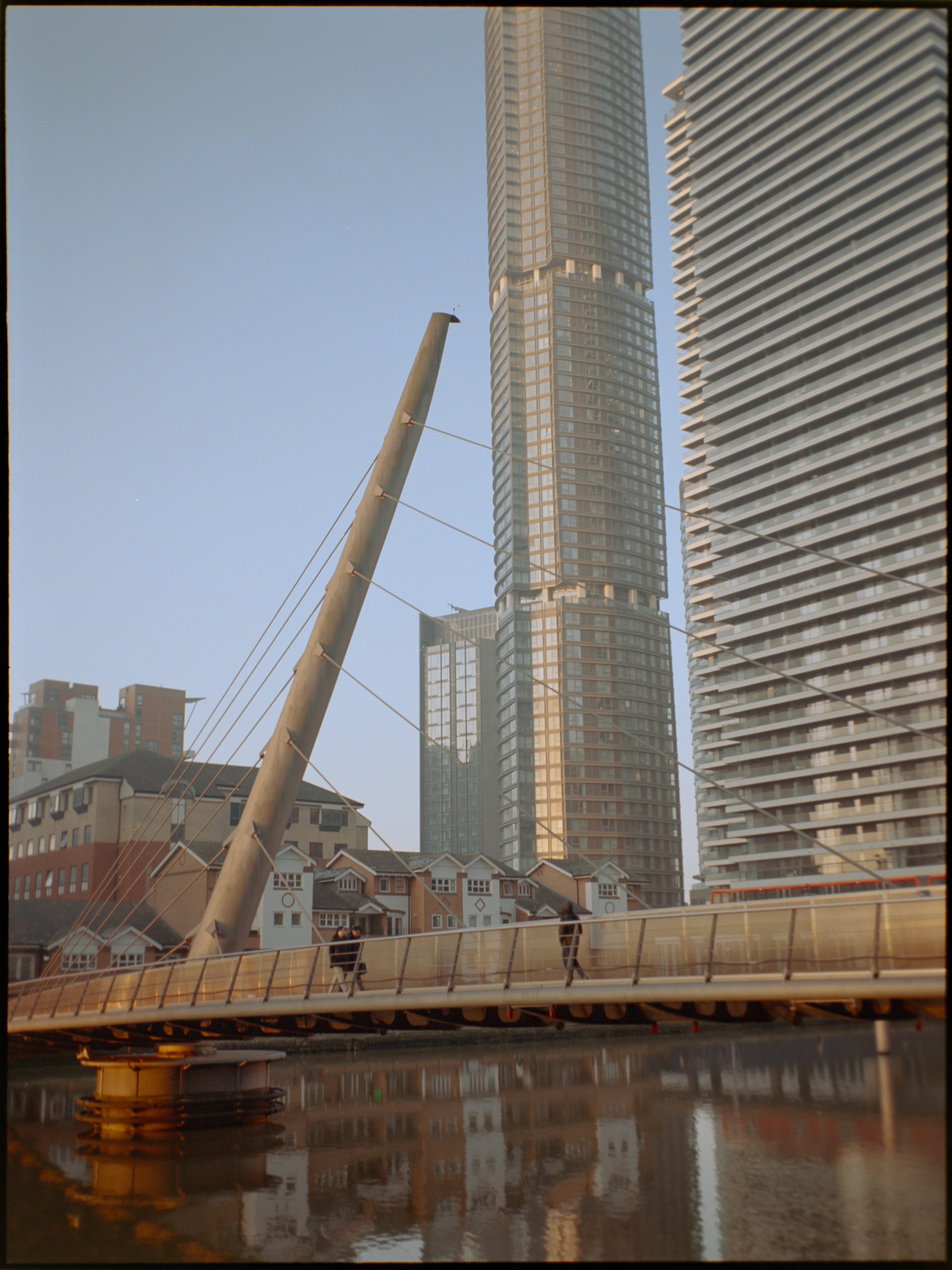 Person walking past glass building facade in Canary Wharf — Kodak Portra 160 film photography London