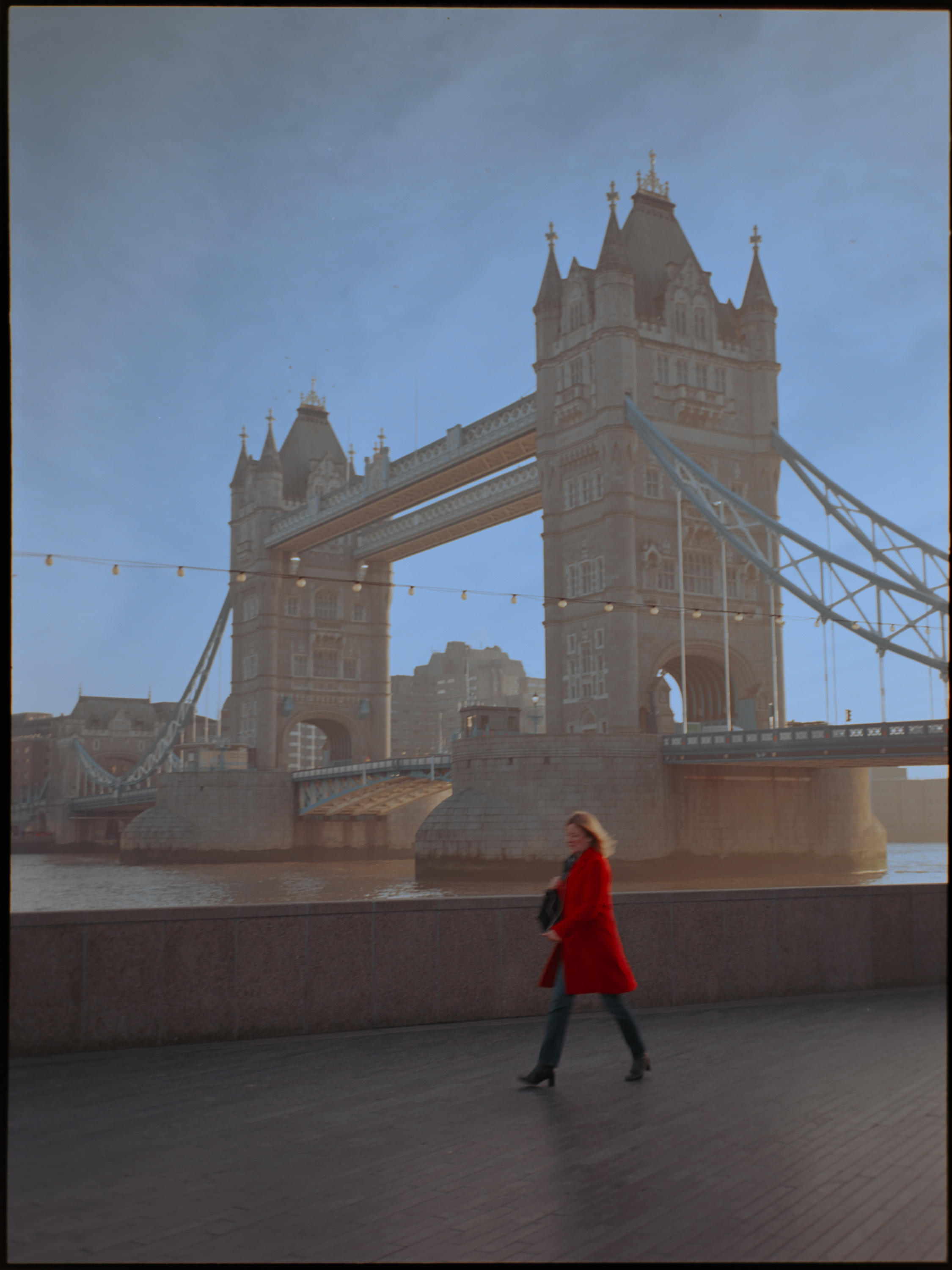 Man descending stairs under Tower Bridge arch — Kodak Ektar 100 with film border visible