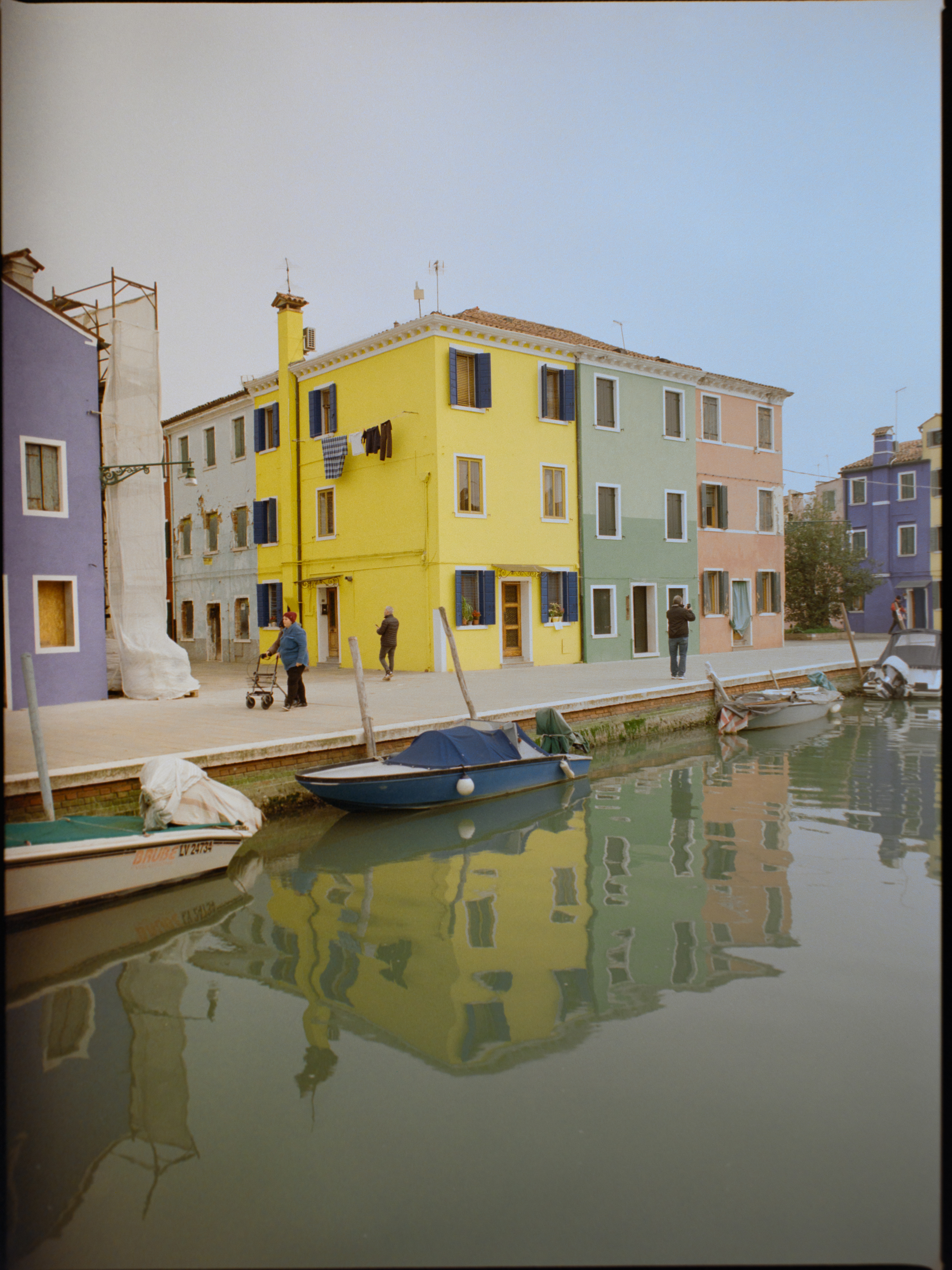 Canal scene with bold yellow house and colourful buildings with locals and boats — Burano on medium format film