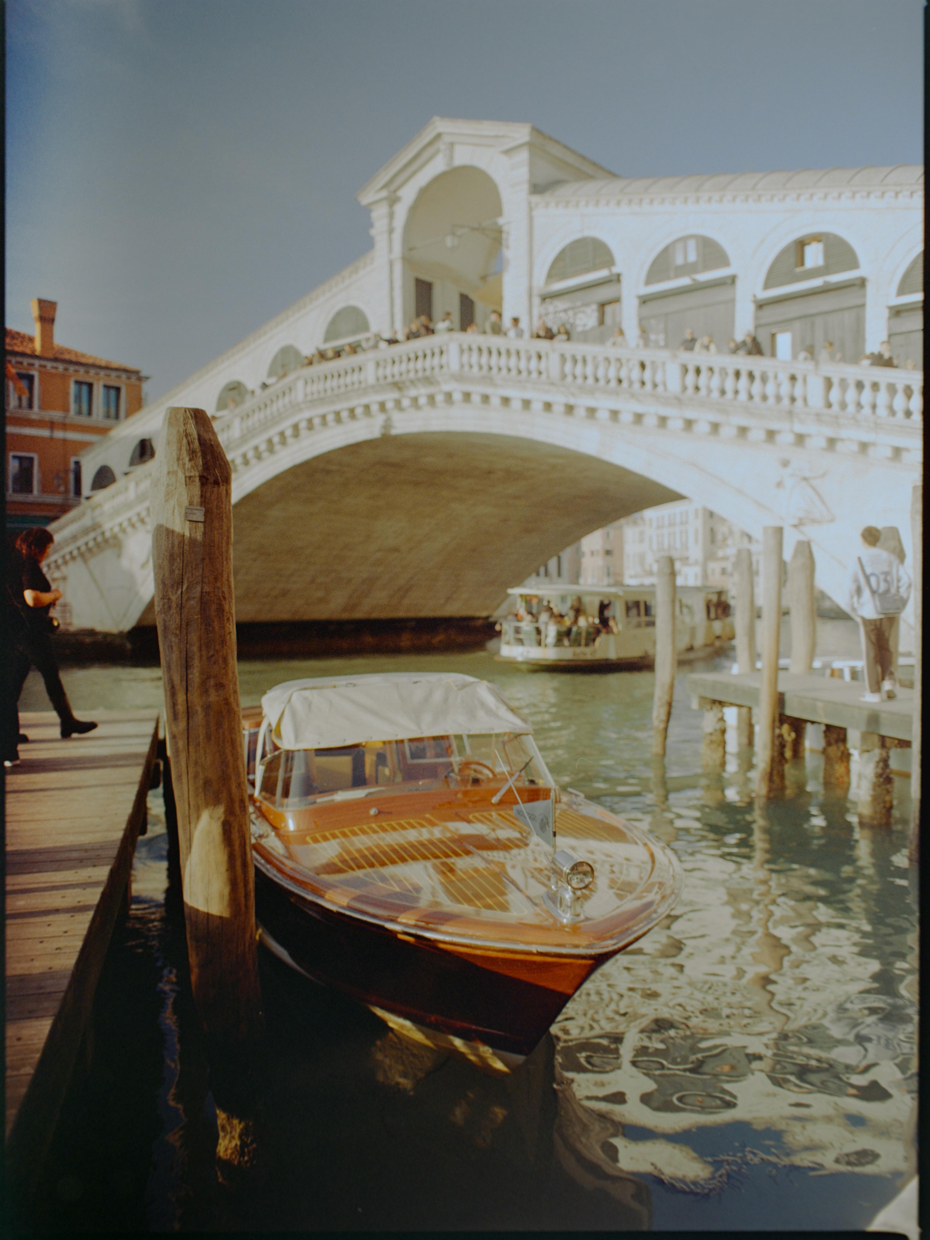 Polished wooden water taxi moored at a dock with the Rialto Bridge behind — Venice on medium format film
