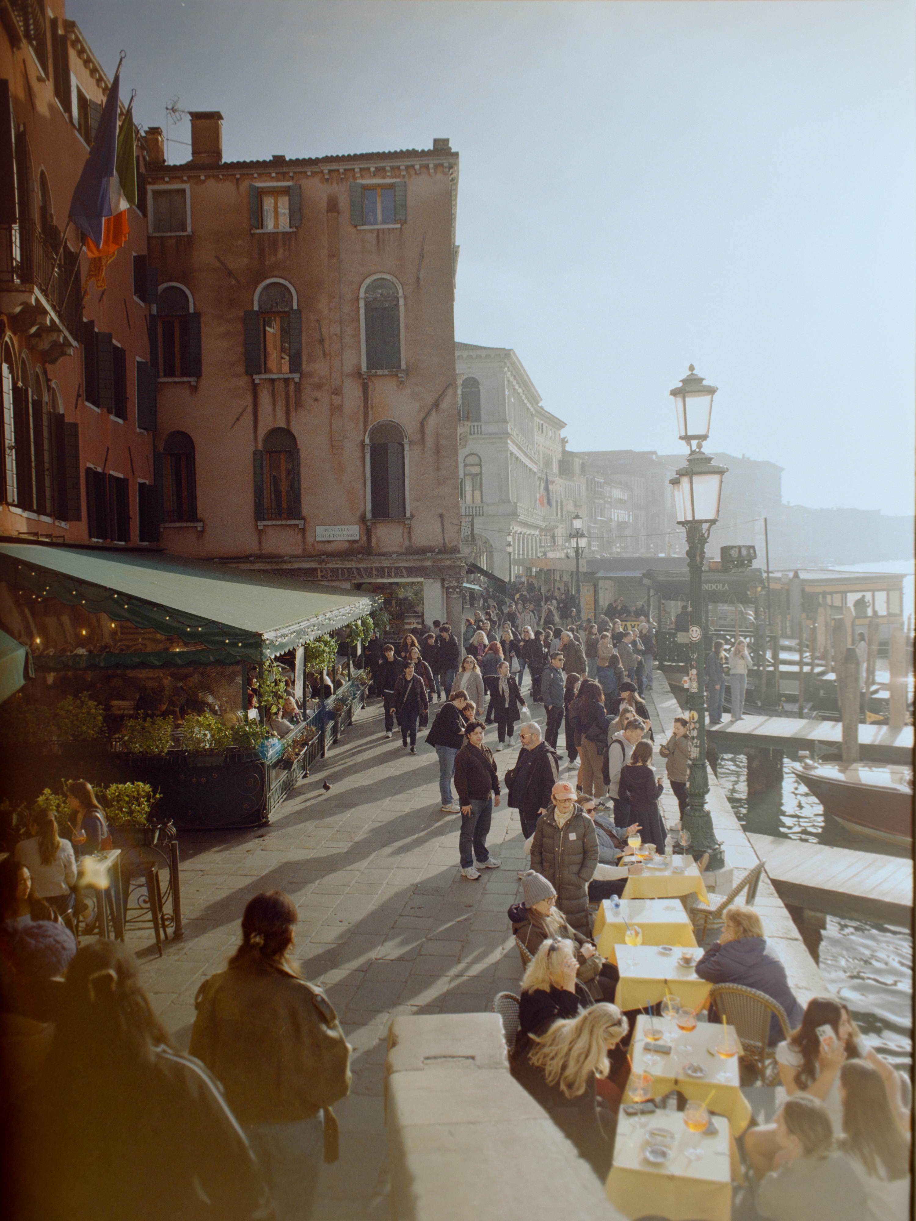 Bustling promenade along the Grand Canal near Rialto with outdoor diners in golden light — Venice on film