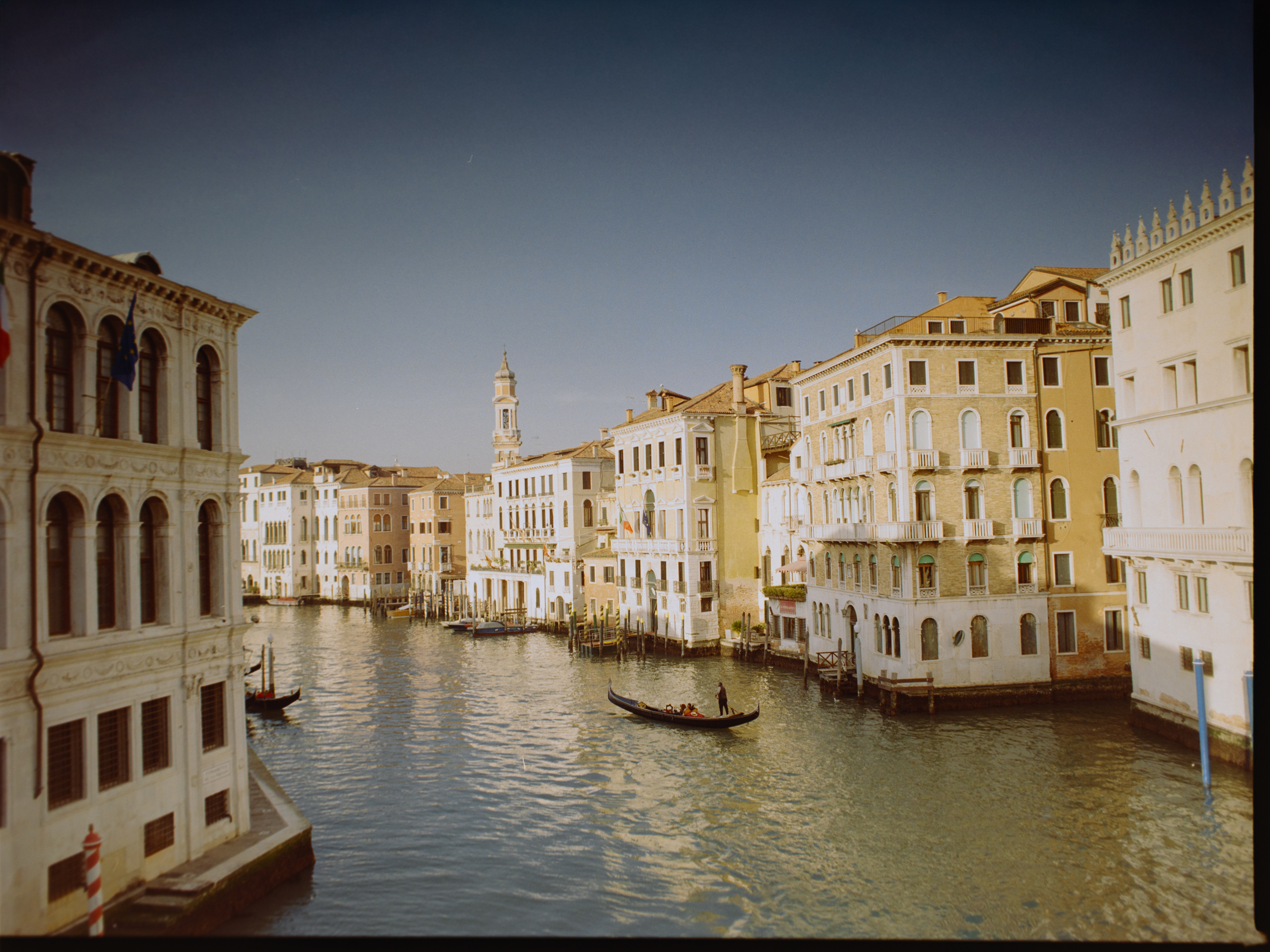 Sweeping view of the Grand Canal from the Rialto Bridge at golden hour with lone gondola — Venice on Kodak Gold 200