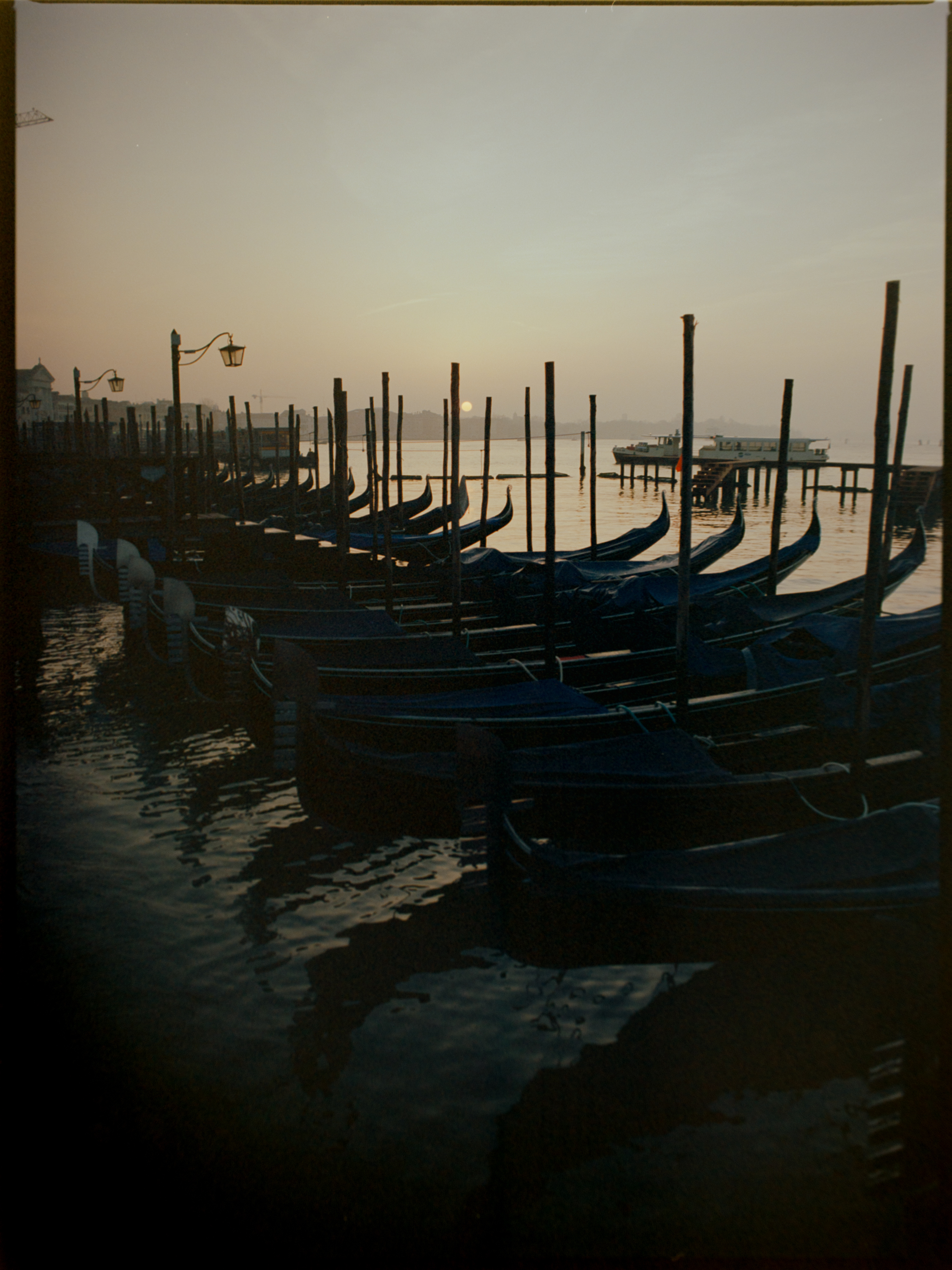 Gondola prows silhouetted at sunrise with San Giorgio Maggiore across the lagoon — Venice on Ektar 100