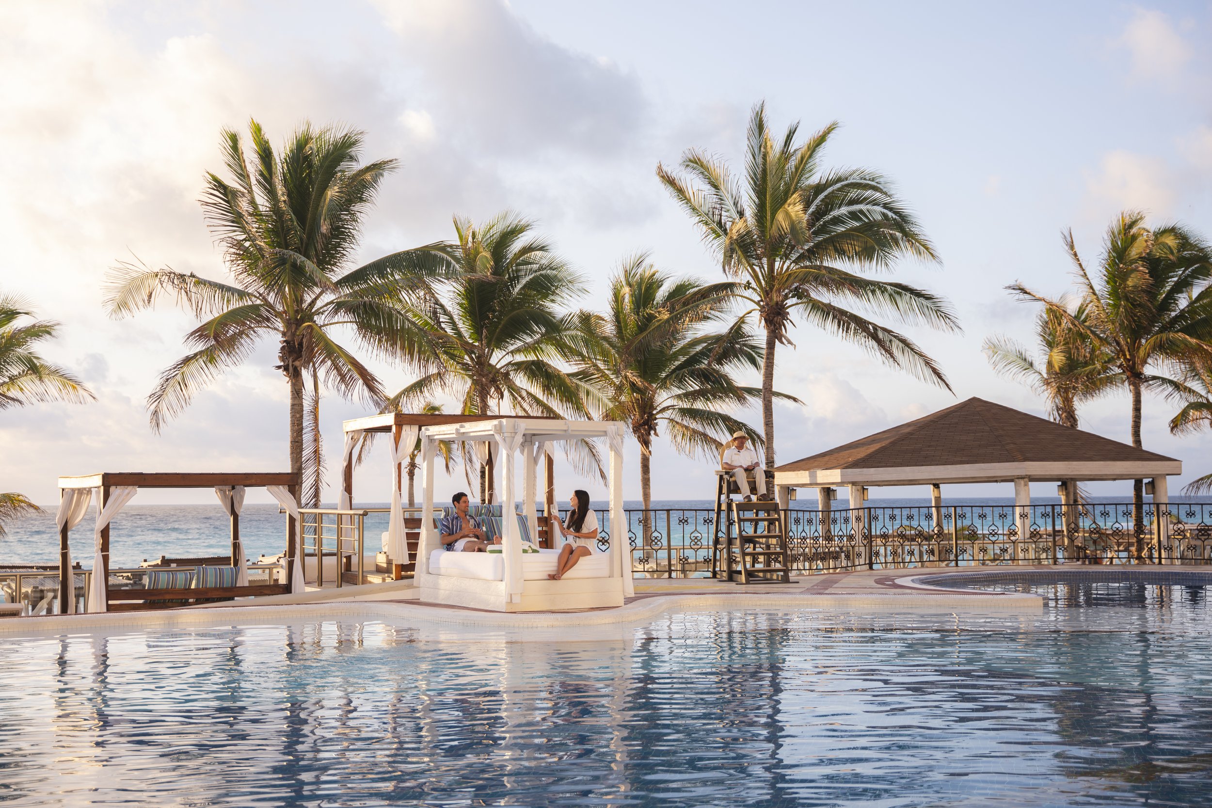 couple luxury poolside cabana cancun resort golden hour palm trees